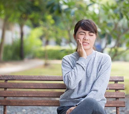Woman sitting on bench should see Midlothian emergency dentist