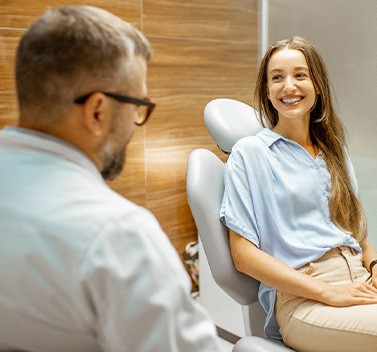a dentist consulting with a smiling woman sitting in a dental chair