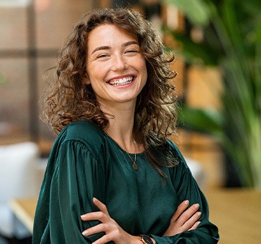 a smiling woman wearing a green blouse with her arms crossed