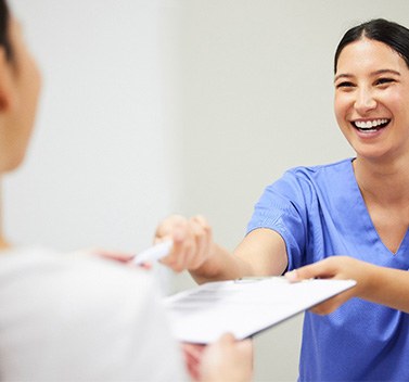 Woman smiling while handing patient form