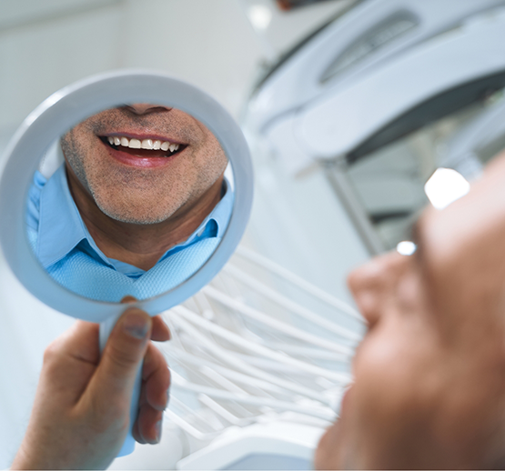 Male dental patient checking smile in mirror
