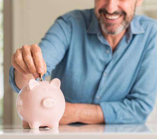 man putting coins into a pink piggy bank