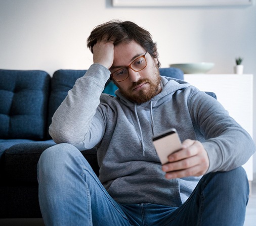 Man with toothache looking at his cell phone 