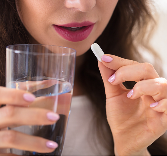 Woman holding glass of water and pill