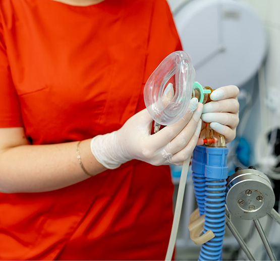Dentist in red shirt holding mask for nitrous oxide sedation