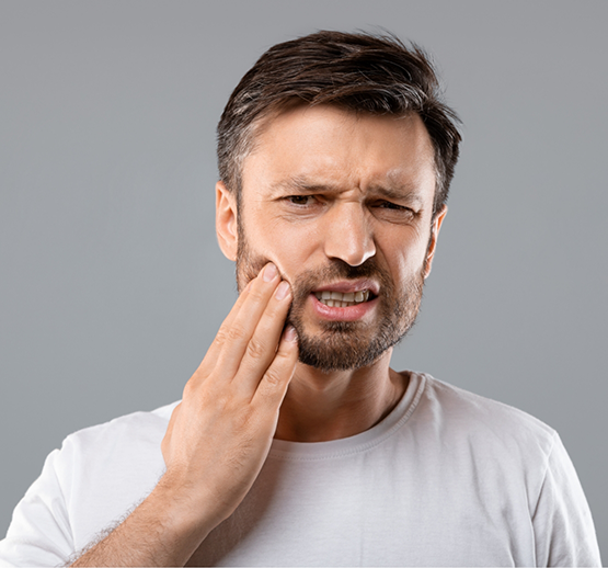 Bearded man in grey shirt with toothache touching side of face
