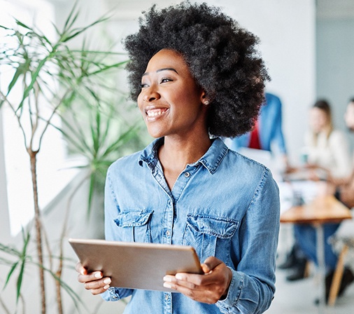 Woman smiling while holding tablet in office