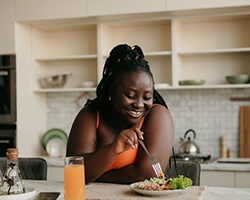 Woman smiling while eating healthy meal at home
