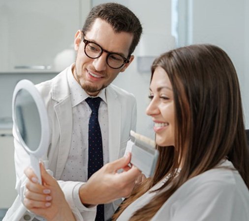 Dental patient smiling at herself in mirror
        