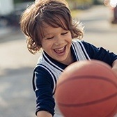 Laughing little boy playing basketball