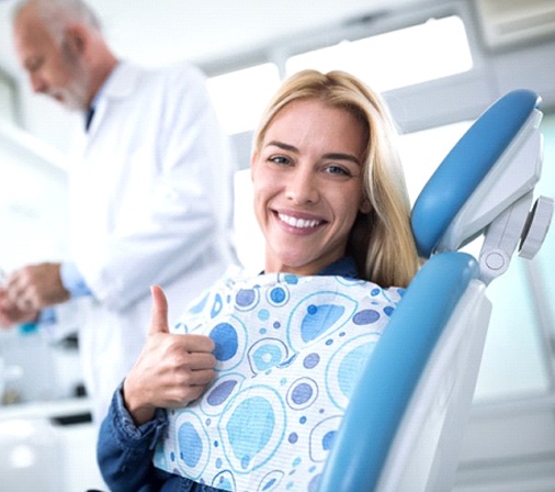 woman giving thumbs up in dental chair