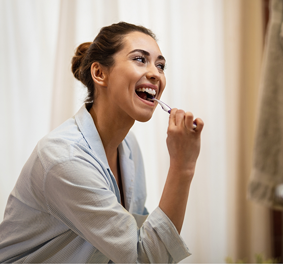 Woman in bathrobe brushing her teeth