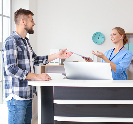 Man talking to female team member at front desk of dental office