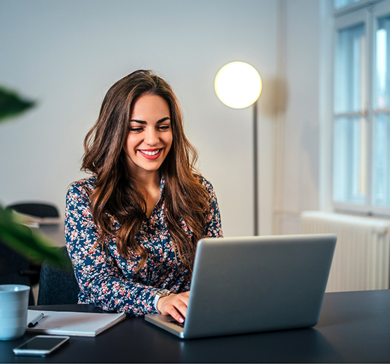 Woman sitting at desk typing on laptop