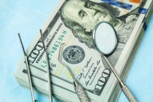 Dental tools on top of $100 bills and dental insurance