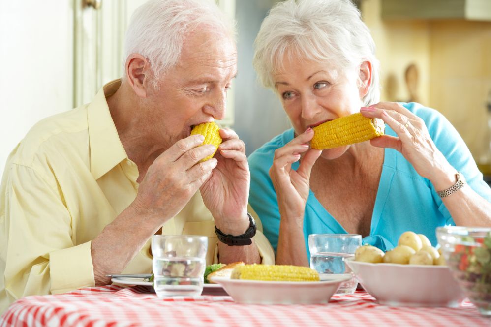 A man and a woman eating corn on the cob