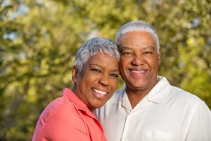 Older couple standing closely together and smiling.